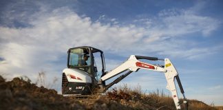 Bobcat E32 R2-Series with boom extended, digging out a trench.
