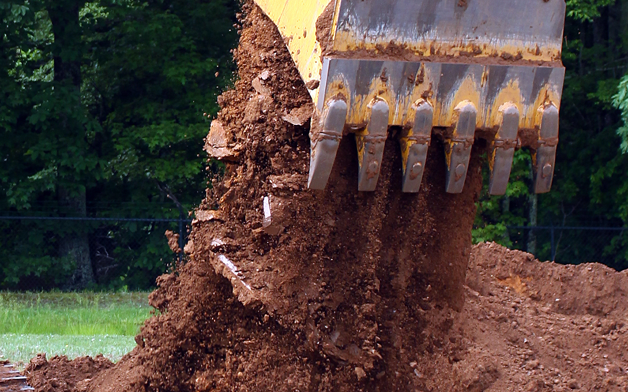 An excavator buckets drops dirt