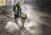 A construction worker uses a Bomag tamper