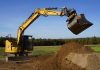 an excavator equipped with a tiltrotator moves dirt