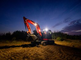 A kubota compact excavator digs at night