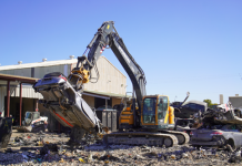 A hyundai material handler lifts a car surrounded by scrap material