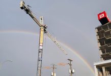 A tower crane on a housing development with a rainbow in the background